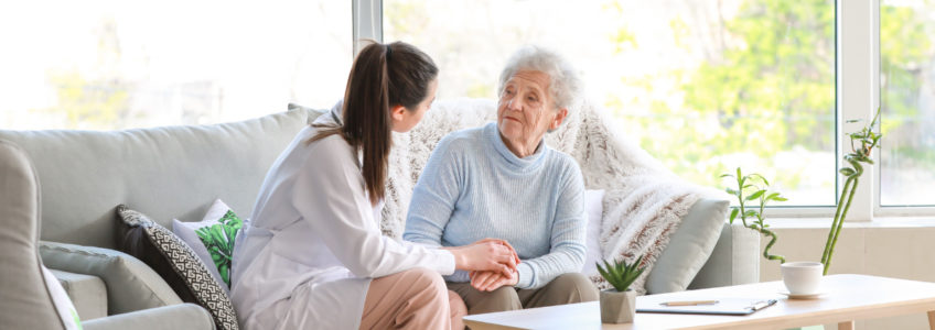 Happy homebound patient sitting on couch with caregiver