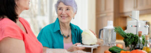 Caring Daughter Or Caretaker And Senior Adult Woman Prepare A Meal